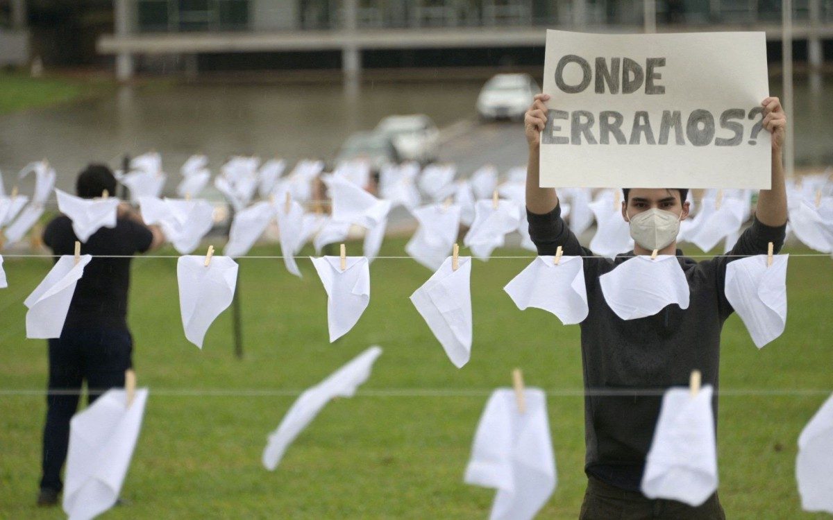 An activist from the Rio de Paz human rights group holds a placard that reads 'Where did we go wrong?' amidst white scarves representing people who died of COVID-19, in front of the National Congress in Brasilia, Brazil, on October 18, 2021. - Brazil on October 8 surpassed 600,000 deaths from Covid-19, the health ministry said. (Photo by EVARISTO SA / AFP)
      Caption - AFP