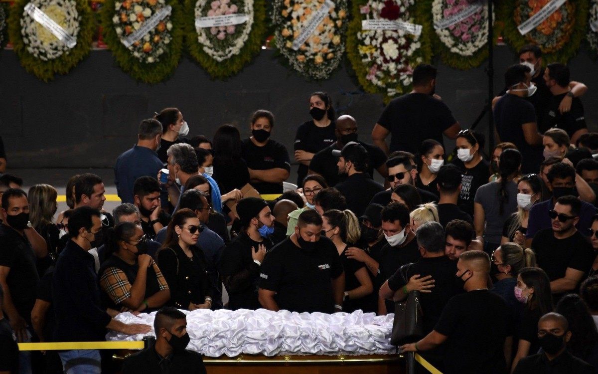 People mourn next to the coffin of Brazilian singer Marilia Mendonca, during her wake at the Arena Goiania sports centre, in Goiania, state of Goias, Brazil, on November 6, 2021. - Marilia Mendonca, 26, one of the most popular of the "sertanejo" genre in Brazil and a Latin Grammy winner, died on the eve along with four other people in an airplane crash on her way to a concert, in the state of Minas Gerais. (Photo by EVARISTO SA / AFP)