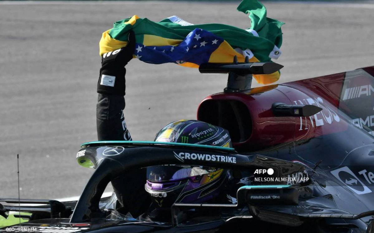 Mercedes' British driver Lewis Hamilton celebrates with a Brazilian flag after winning Brazil's Formula One Sao Paulo Grand Prix at the Autodromo Jose Carlos Pace, or Interlagos racetrack, in Sao Paulo, on November 14, 2021. (Photo by NELSON ALMEIDA / AFP)