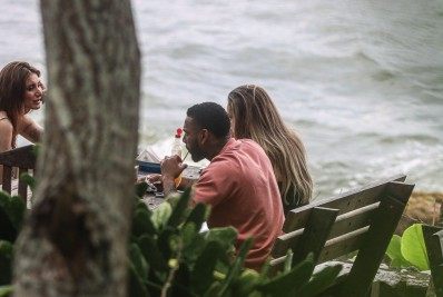 Nego do Borel curte a tarde com duas mulheres em restaurante à beira do mar