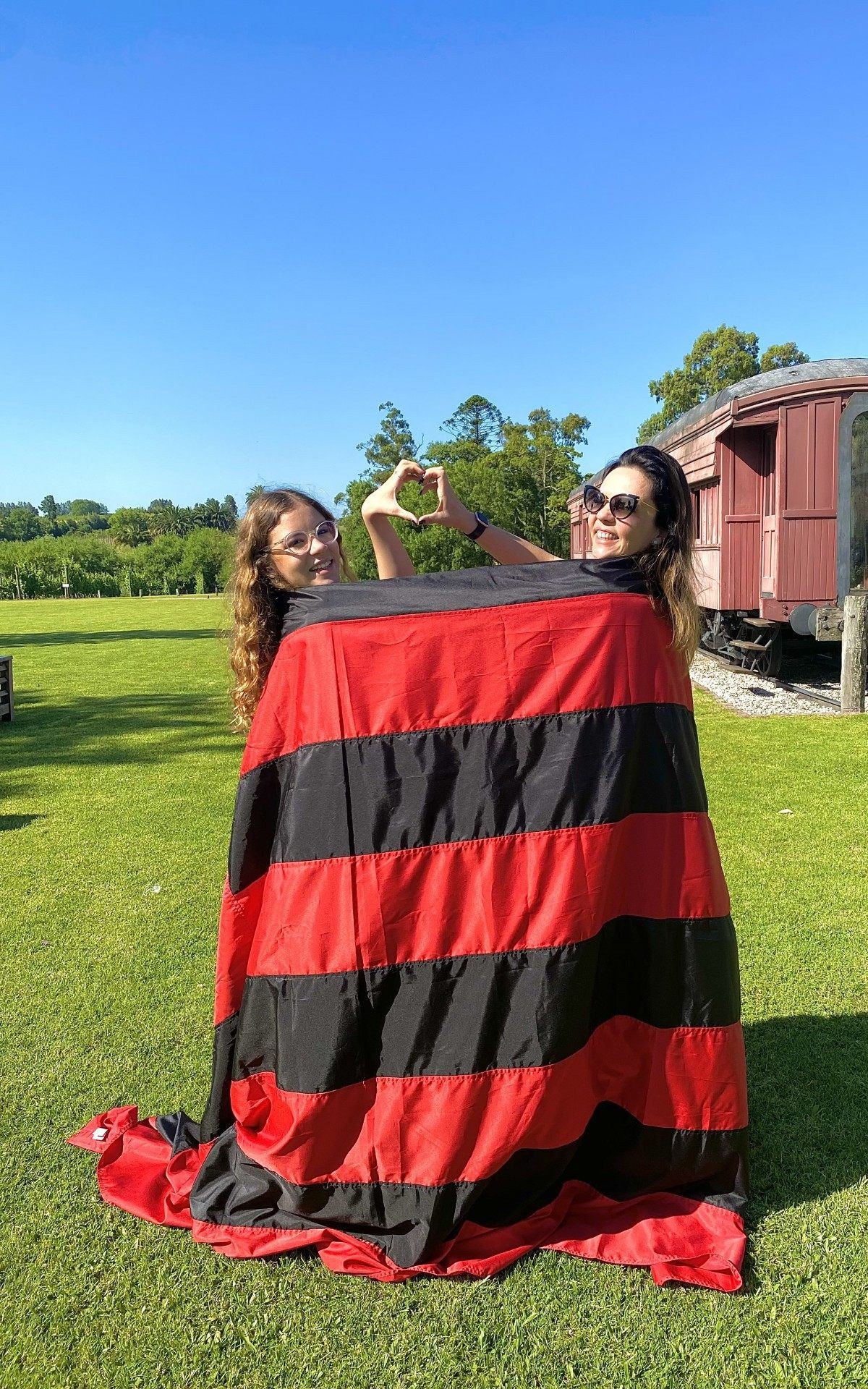 M&atilde;e e filha, Cida e Lara Amaral, posam com a bandeira do Flamengo, no Uruguai