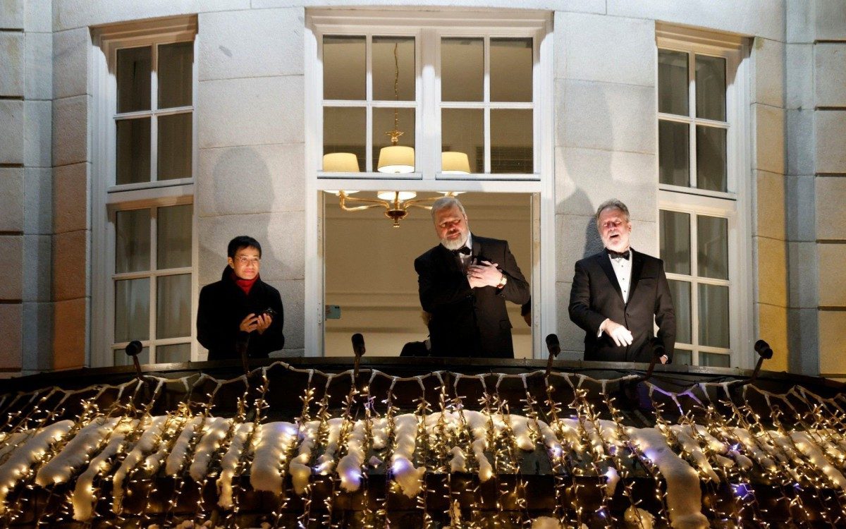 Nobel Peace Prize laureates Maria Ressa of the Philippines (L) and Dmitry Muratov of Russia (C) react next to US Nobel Peace Prize 2020 laureate David Beasley as they greet the crowd from the balcony of the Grand Hotel in Oslo on December 10, 2021, following the Nobel Peace Prize gala award ceremony. - Investigative journalists Maria Ressa of the Philippines and Dmitry Muratov of Russia won the prestigious award earlier this month for their work promoting freedom of expression at a time when liberty of the press is increasingly under threat. (Photo by Odd ANDERSEN / AFP) - AFP