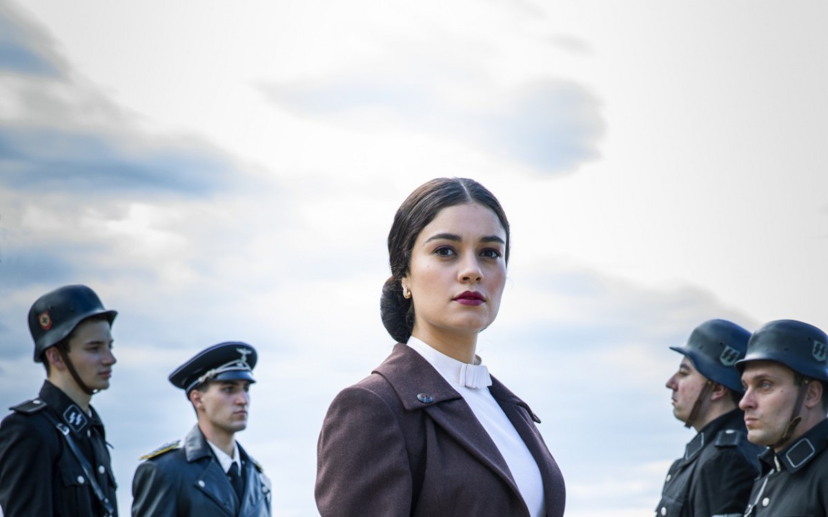 Angel of Hamburg
O Anjo de Hamburgo 
EPK
Item 3 - Cap 1 - Cena 6A &ndash; Vivi ( Gabriela Petry ) &eacute; atacada por jovens. Zumkle ( Peter Ketnath ) a salva. Repreende Hans ( Nicolas Ahnert ). Fotos: Essa cena &eacute; muito importante. Zumkle &eacute; o nosso antagonista, capit&atilde;o da tropa nazista. Ele tem um romance secreto com Vivi, que &eacute; judia. Precisamos de fotos de cena que tenham o ar desse &ldquo;relacionamento secreto&rdquo; entre os dois.  Angel of Hamburg
O Anjo de Hamburgo 
EPK
 Item 4 - Cap 2 - Cena 57 &ndash; Aracy ( Sophie Charlotte ) v&ecirc; indignada judeus de todas as idades sendo expulsos de suas casas. Fotos: Precisamos de fotos que traduzam o clima tenso do momento. Judeus sendo expulsos. Se os judeus estiverem com as estrelas amarelas, capturar isso tamb&eacute;m. 
 