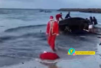 Papai Noel cai na água após chegar de jangada em praia; Assista