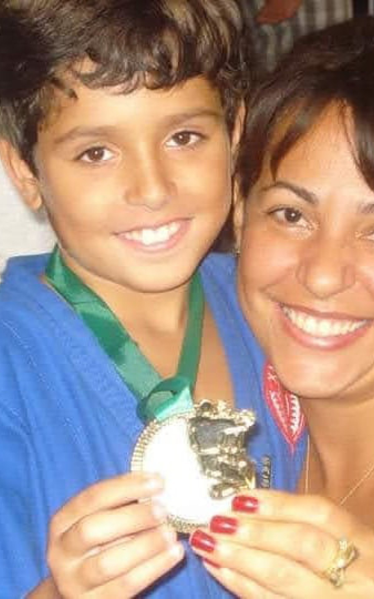 Rafael ao lado de sua m&atilde;e, com uma medalha conquistada em um torneio de jiu-jitsu quando era crian&ccedil;a