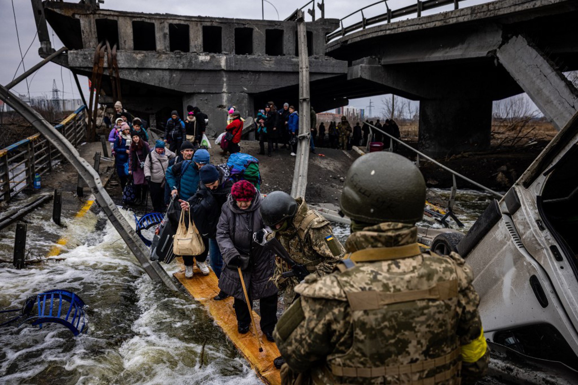 Evacuados atravessarem uma ponte destruída enquanto fugiam da cidade de Irpin, a noroeste de Kiev - DIMITAR DILKOFF / AFP