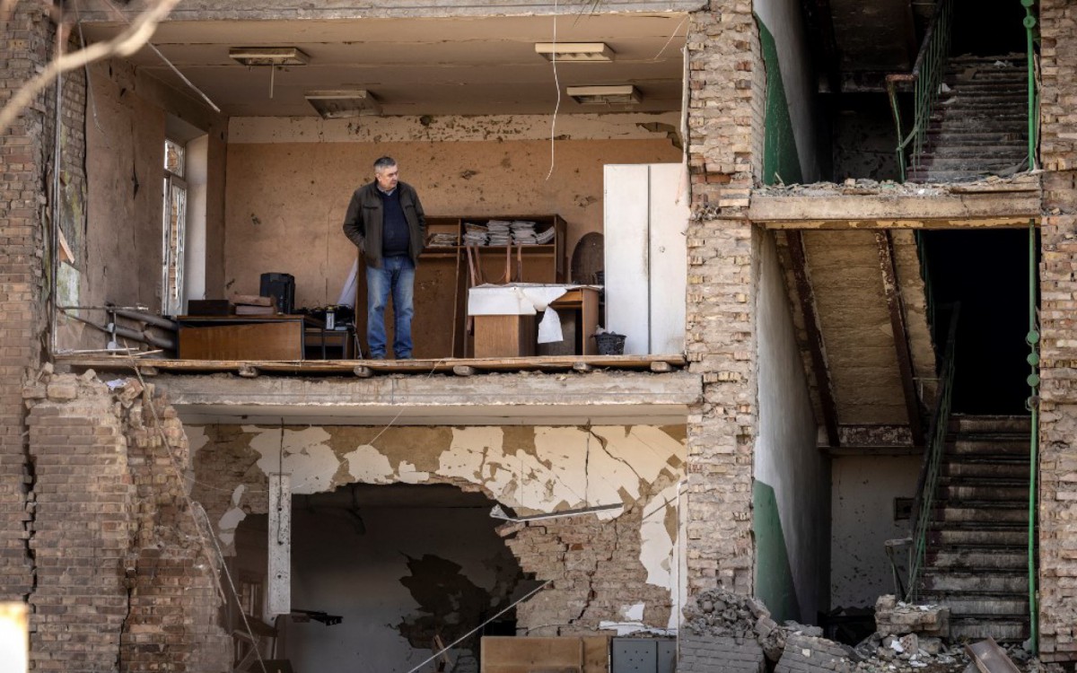 Pessoas passam por um prédio danificado no complexo militar-industrial da empresa Vizar, depois que o local foi atingido por ataques russos durante a noite, na cidade de Vyshneve, subúrbios do sudoeste de Kiev, na Ucrânia - FADEL SENNA / AFP