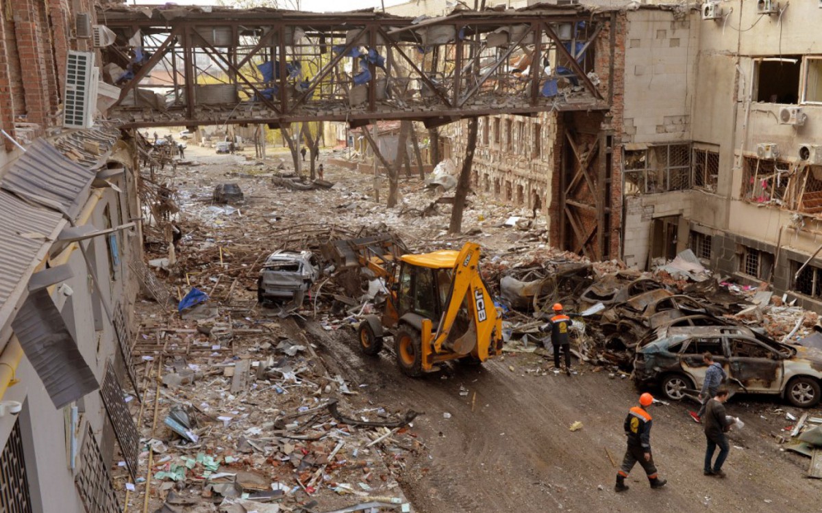 Trabalhadores comunitários limpam prédios destruídos após bombardeios, matando duas pessoas e ferindo outras dezoito, de acordo com a promotoria da região de Kharkiv, na cidade ucraniana, neste sábado, 16