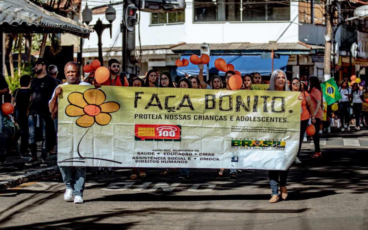 O vice-prefeito Natalício da Farmácia e a secretária de Assistência Social e Direitos Humanos, Telma Couto, seguram um cartaz durante a caminhada - Secom PMG - Reprodução