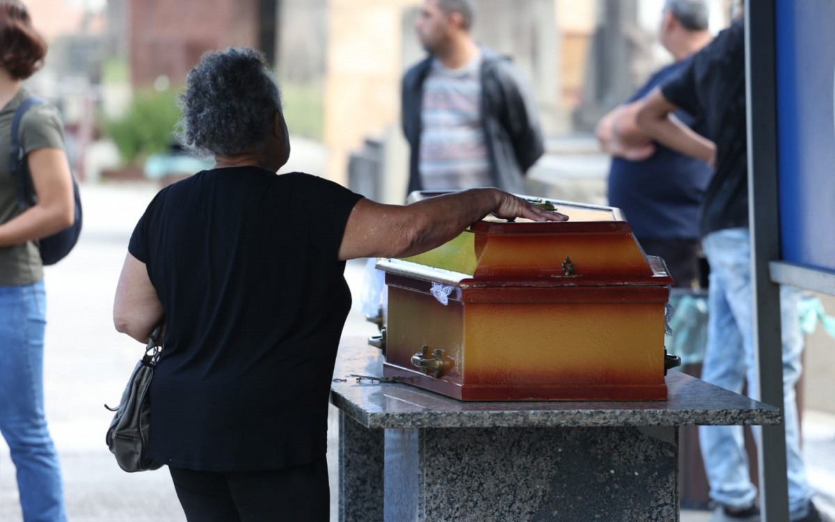 Dona Divone Ferreira da Cunha, de 72 anos, se despede da filha durante sepultamento