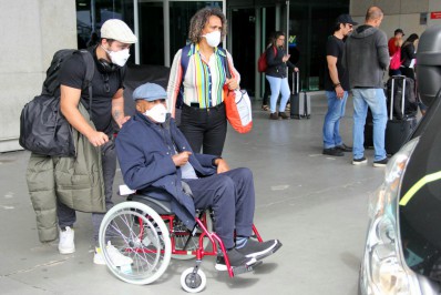 Em cadeira de rodas, Milton Nascimento desembarca em aeroporto do Rio