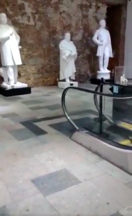 Capturas de tela dos segundos iniciais do v&iacute;deo investigado pelo Comprova que mostram as est&aacute;tuas, a escada rolante e, logo depois, a placa com a tarja preta no nome do ex-presidente Lula - Reprodu&ccedil;&atilde;o