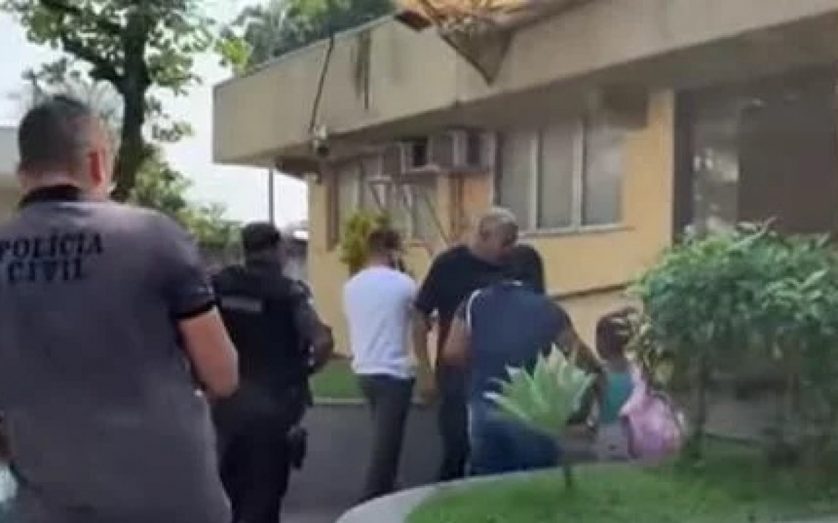 O cabo PM Tarc&iacute;sio de Assis Nunes (camisa branca) na chegada a Deam em Belford Roxo