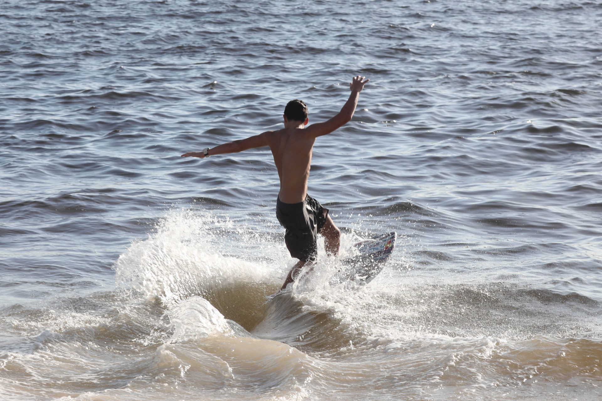 Jovem aproveita ondas para surfar na Praia de Icara&iacute;, em Niter&oacute;i - Pedro Ivo / Ag&ecirc;ncia O Dia