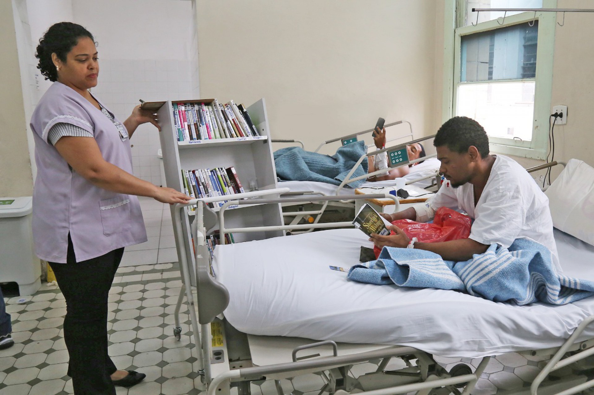 J&aacute; o paciente Walace do Nascimento, de 24 anos, pegou emprestado o t&iacute;tulo "Sherlock Holmes, o Signo dos Quatro", de Arthur Conan Doyle - Divulga&ccedil;&atilde;o / SES