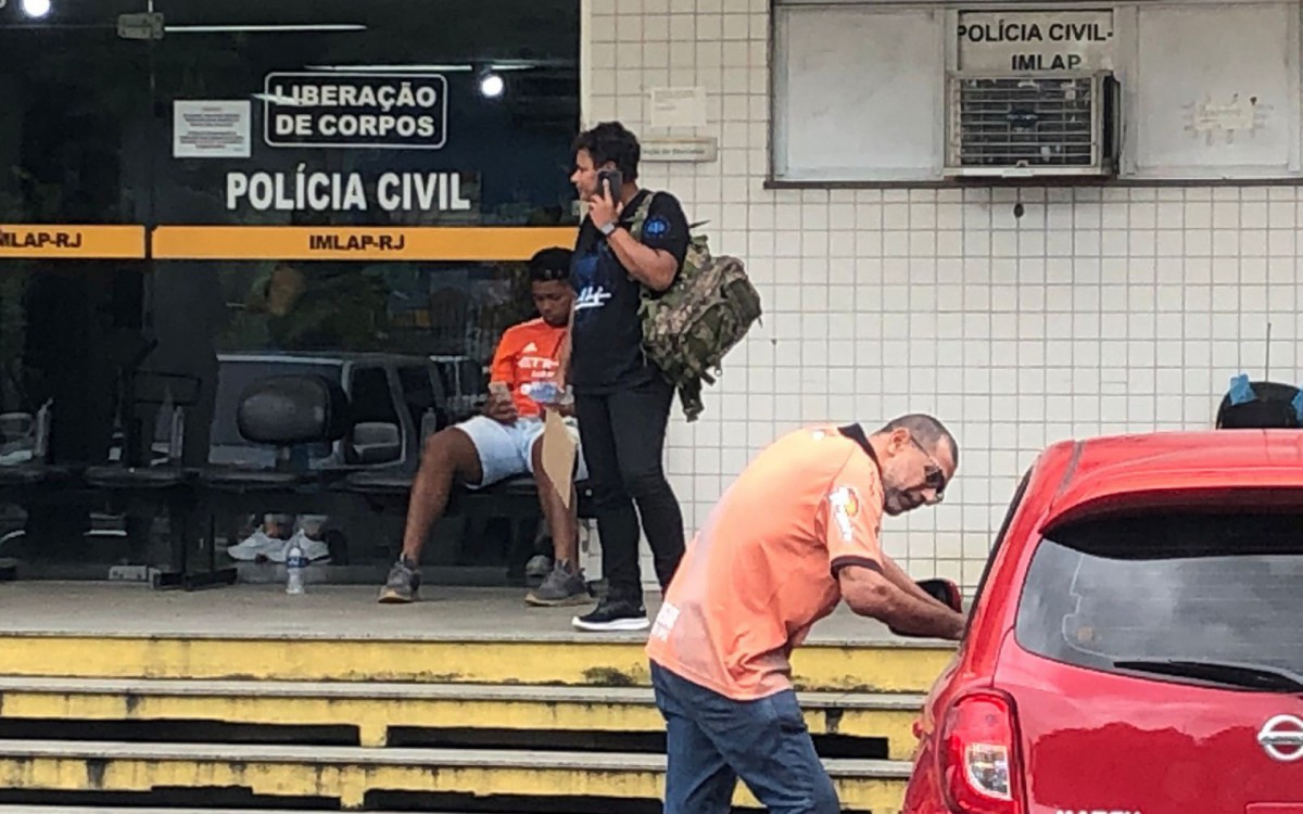 O irmão do policial do Bope (de blusa laranja) esteve no IML nesta quarta para liberação do corpo - Pedro Medeiros/Agência O DIA
