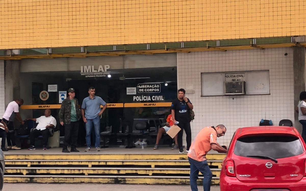 O irmão do policial do Bope (de blusa laranja) esteve no IML nesta quarta para liberação do corpo - Pedro Medeiros/Agência O DIA