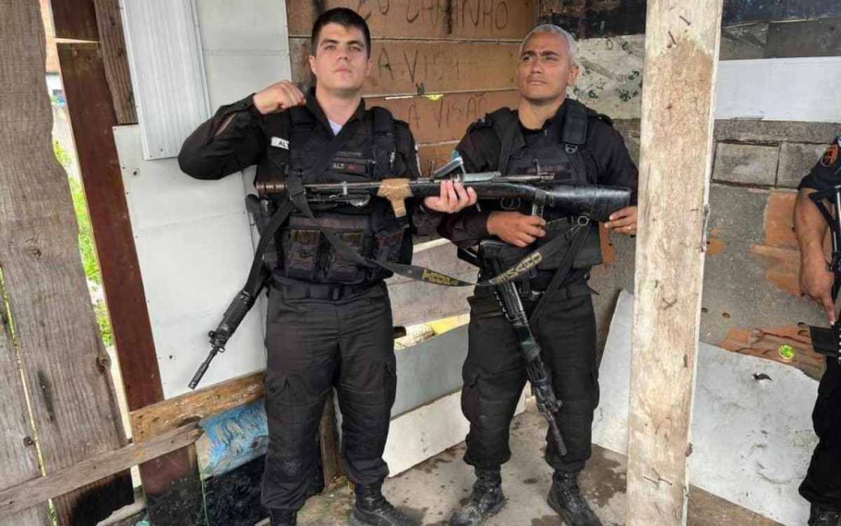 Os policiais militares com o fuzil apreendido