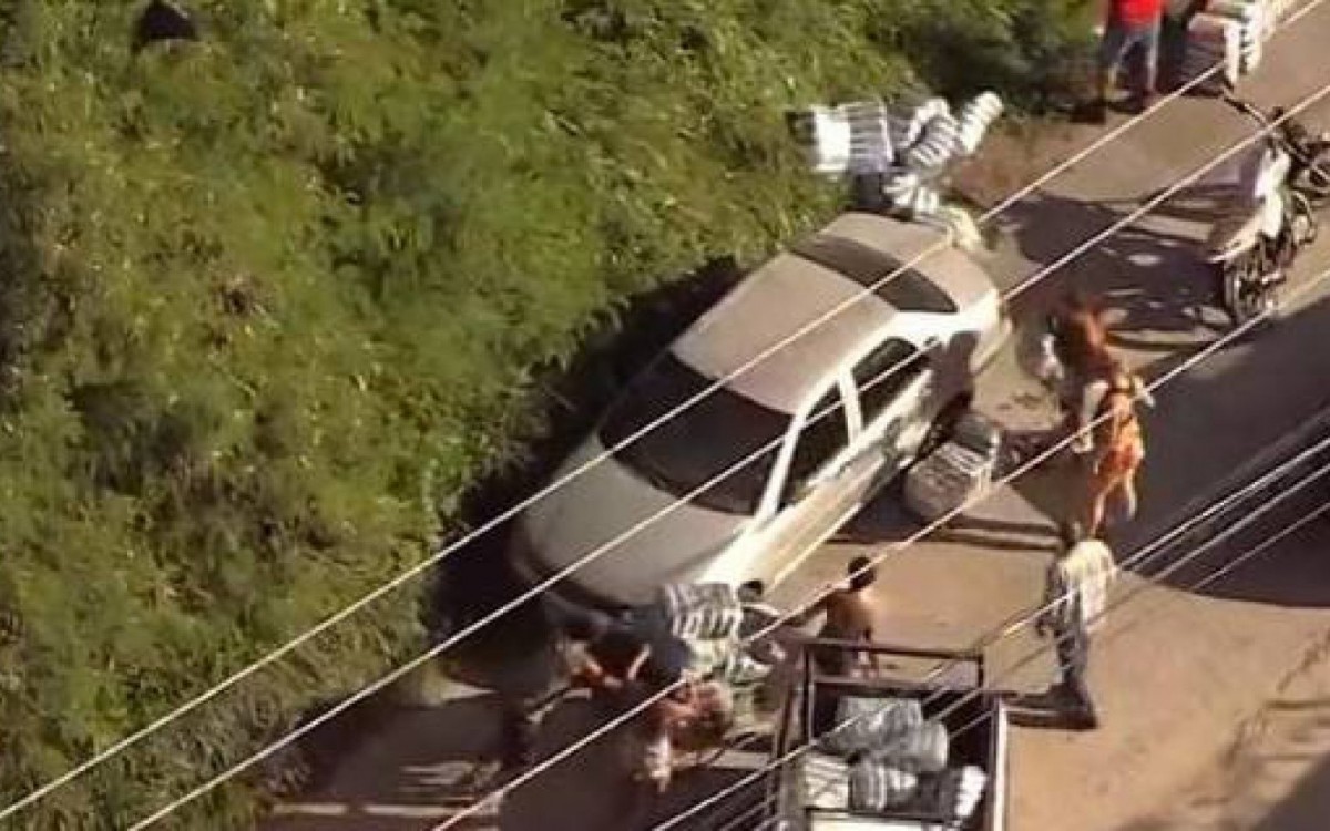 Durante o acidente, pessoas ainda roubaram a carga de arroz que caiu do caminhão - Reprodução/TV Globo