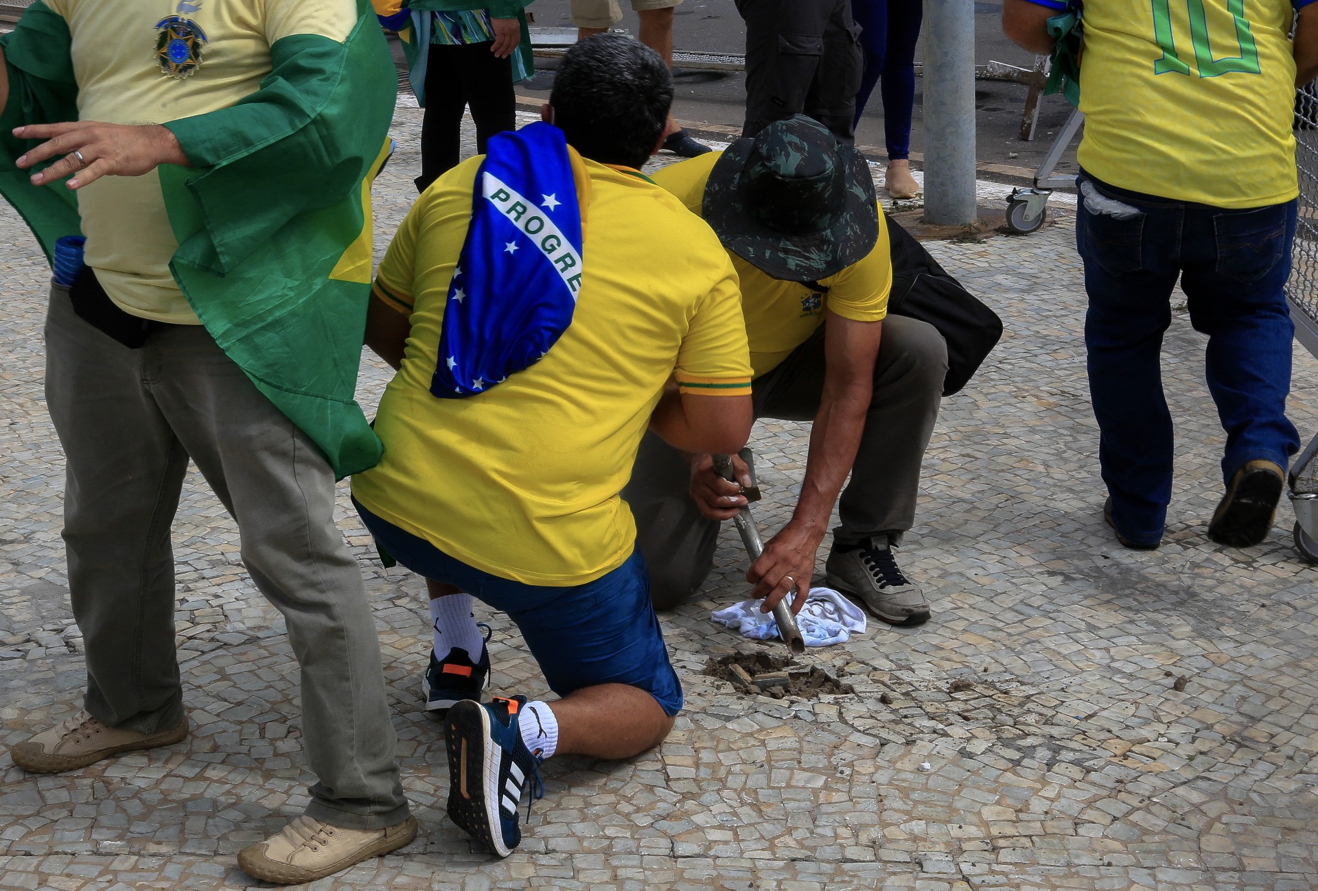 Supporters of Brazilian former President Jair Bolsonaro damage the sidewalk to obtain stones during clashes with riot police outside Planalto Presidential Palace, in Brasilia on January 8, 2023. Hundreds of supporters of Brazil's far-right ex-president Jair Bolsonaro broke through police barricades and stormed into Congress, the presidential palace and the Supreme Court Sunday, in a dramatic protest against President Luiz Inacio Lula da Silva's inauguration last week.
 - Sergio Lima / AFP