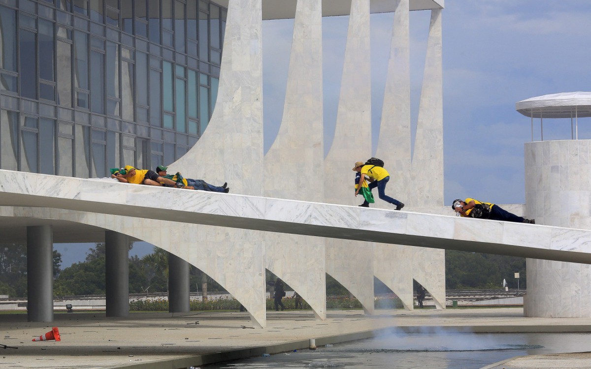 Supporters of Brazilian former President Jair Bolsonaro cover their faces as security forces fire tear gas during clashes as they invade Planalto Presidential Palace in Brasilia on January 8, 2023. Brazilian police used tear gas Sunday to repel hundreds of supporters of far-right ex-president Jair Bolsonaro after they stormed onto Congress grounds one week after President Luis Inacio Lula da Silva's inauguration, an AFP photographer witnessed.
- Sergio LIMA / AFP