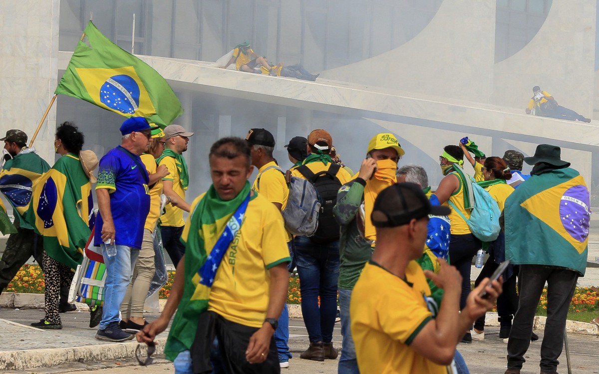 Supporters of Brazilian former President Jair Bolsonaro invading Planalto Presidential Palace are affected by tear gas fired by security forces, in Brasilia on January 8, 2023. Hundreds of supporters of Brazil's far-right ex-president Jair Bolsonaro broke through police barricades and stormed into Congress, the presidential palace and the Supreme Court Sunday, in a dramatic protest against President Luiz Inacio Lula da Silva's inauguration last week.
 - Sergio Lima / AFP