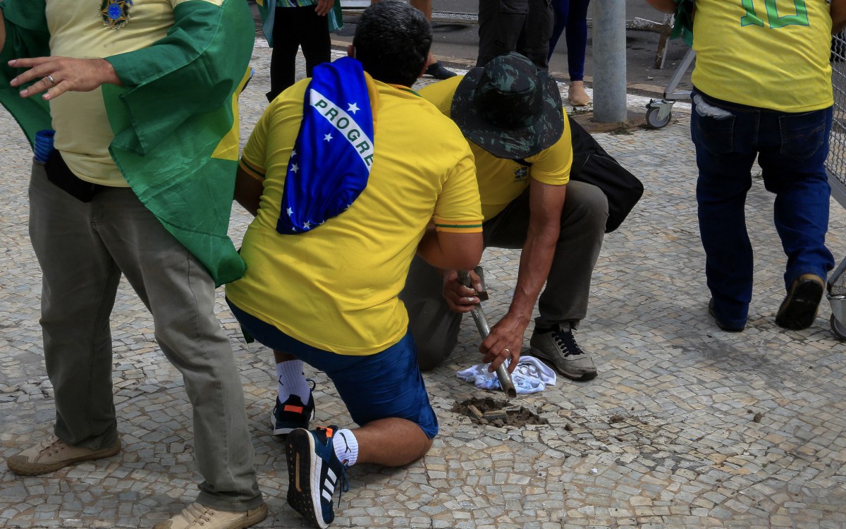 Supporters of Brazilian former President Jair Bolsonaro damage the sidewalk to obtain stones during clashes with riot police outside Planalto Presidential Palace, in Brasilia on January 8, 2023. Hundreds of supporters of Brazil's far-right ex-president Jair Bolsonaro broke through police barricades and stormed into Congress, the presidential palace and the Supreme Court Sunday, in a dramatic protest against President Luiz Inacio Lula da Silva's inauguration last week.
 - Sergio Lima / AFP