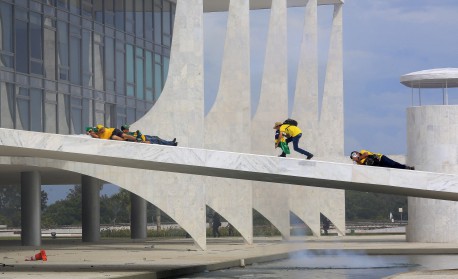 Supporters of Brazilian former President Jair Bolsonaro cover their faces as security forces fire tear gas during clashes as they invade Planalto Presidential Palace in Brasilia on January 8, 2023. Brazilian police used tear gas Sunday to repel hundreds of supporters of far-right ex-president Jair Bolsonaro after they stormed onto Congress grounds one week after President Luis Inacio Lula da Silva's inauguration, an AFP photographer witnessed.
 - Sergio LIMA / AFP