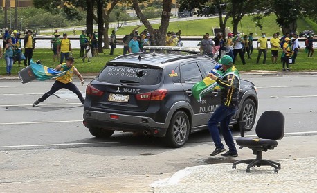 Supporters of Brazilian former President Jair Bolsonaro attack a vehicle of the Military Police during clashes outside Planalto Presidential Palace in Brasilia on January 8, 2023. Hundreds of supporters of Brazil's far-right ex-president Jair Bolsonaro broke through police barricades and stormed into Congress, the presidential palace and the Supreme Court Sunday, in a dramatic protest against President Luiz Inacio Lula da Silva's inauguration last week.
 - Sergio Lima / AFP