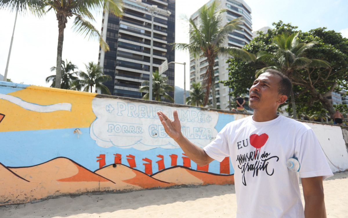 André Rongo no painel pintado em São Conrado, com o tema 'Praia limpa por gentileza' - Pedro Ivo/ Agência O Dia