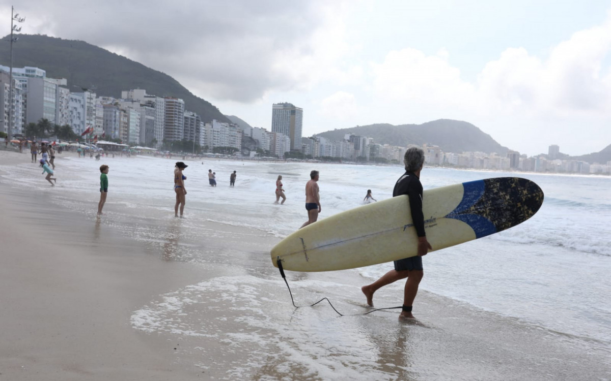 Surfista e banhistas se preparam para entrar no mar