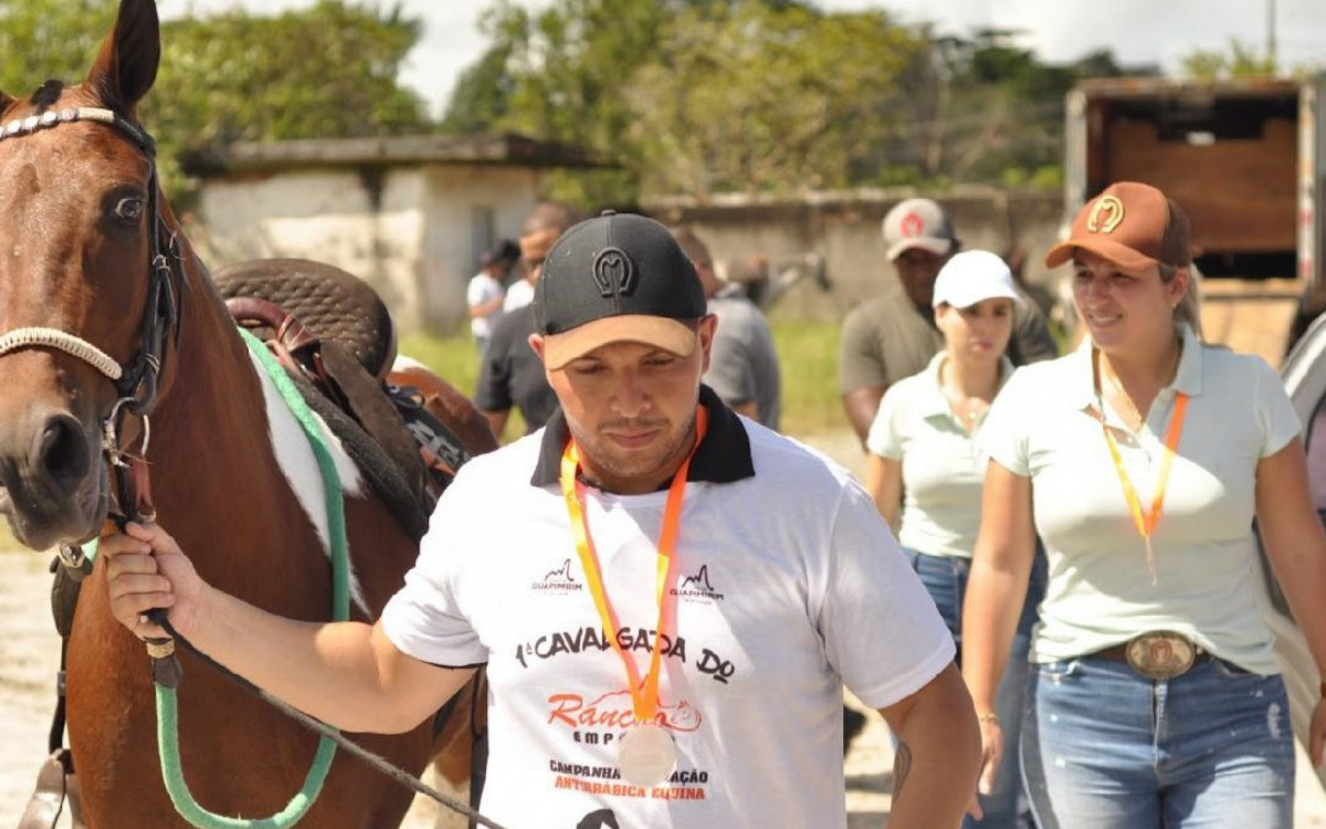 O empres&aacute;rio Ded&eacute; Borret, organizador da cavalgada, com um cavalo; ao fundo, de bon&eacute; marrom, a prefeita de Guapimirim, Marina Rocha