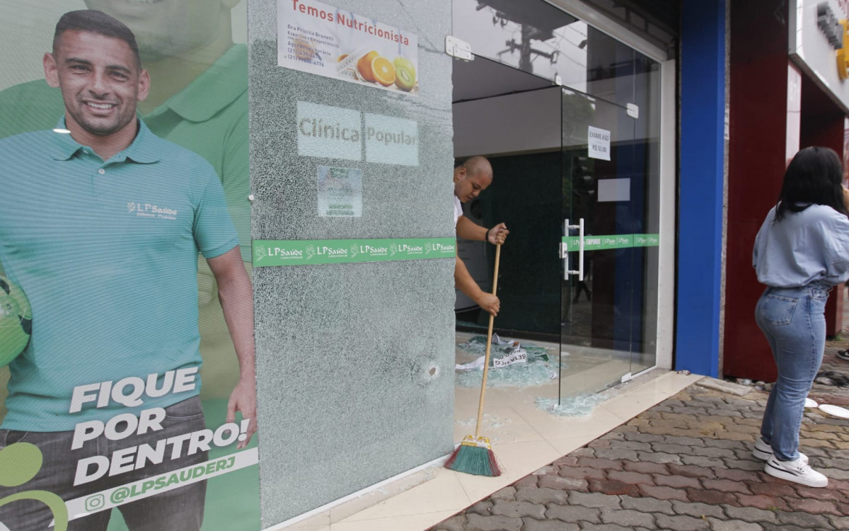 Vidraça de loja próxima à agência bancária também foi atingida por tiros e ficou destruída - Reginaldo Pimenta/Agência O Dia