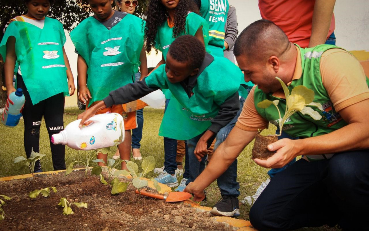 Secret&aacute;rio Igo Menezes observa um aluno regando uma planta no Ciep Constantino Reis