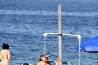 Betty Faria curte dia de praia e se refresca em ducha 