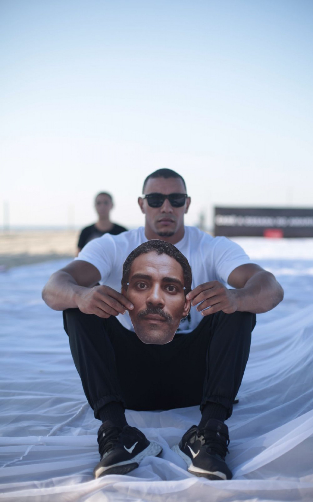 Filhos do Amarildo seguram máscaras do rosto do pai na praia de Copacabana - Rio de Paz/Divulgação