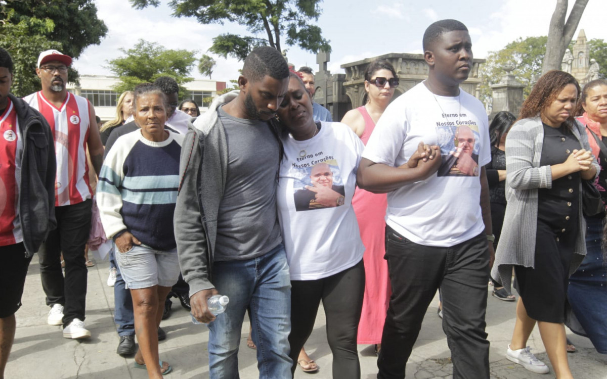&Eacute;rica Oliveira, esposa de David, e outros familiares seguraram cartaz com pedido de paz nas comunidades durante o sepultamento