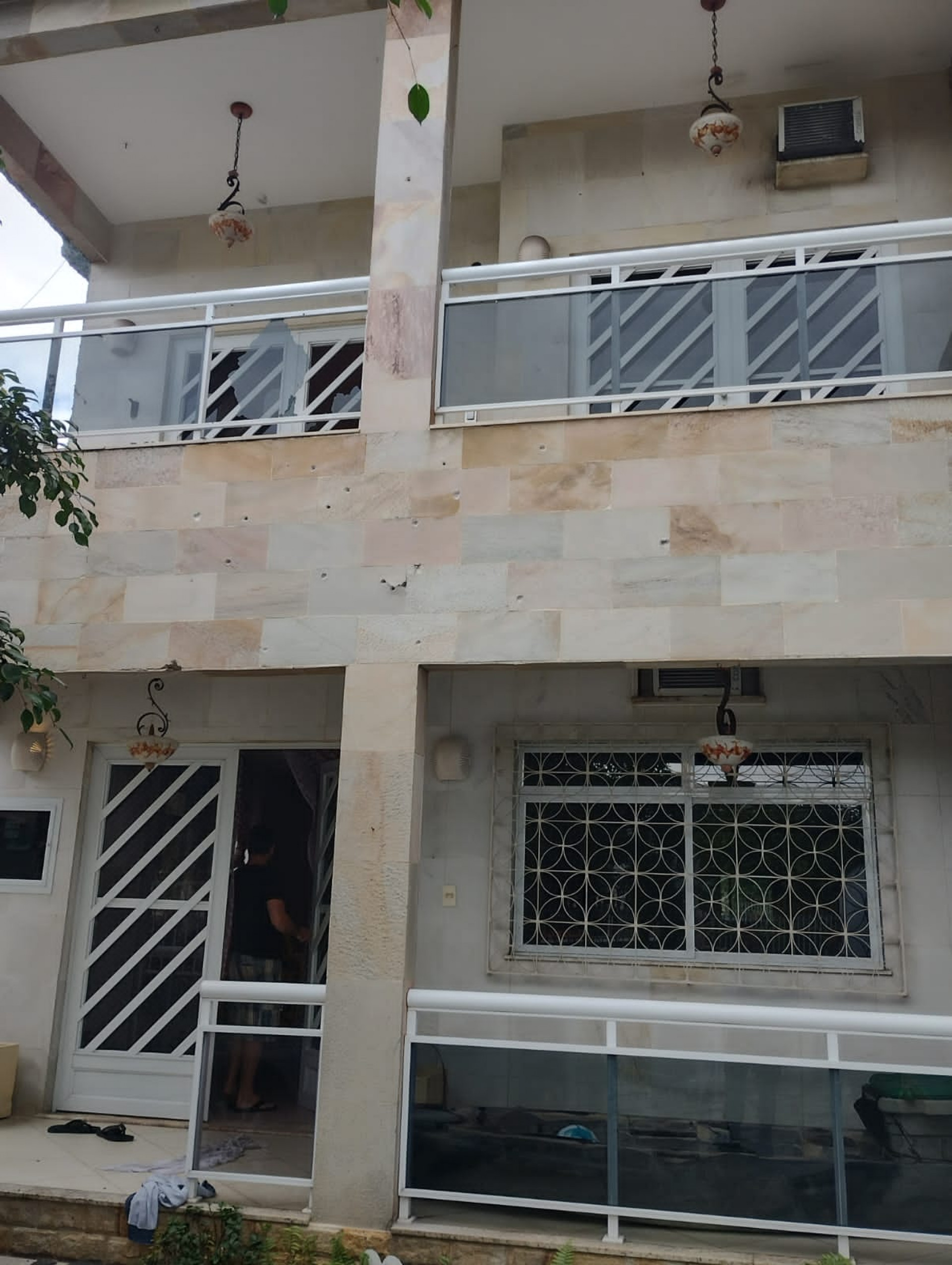 Fachada da residência com marcas dos disparos e os vidros da sacada quebrados