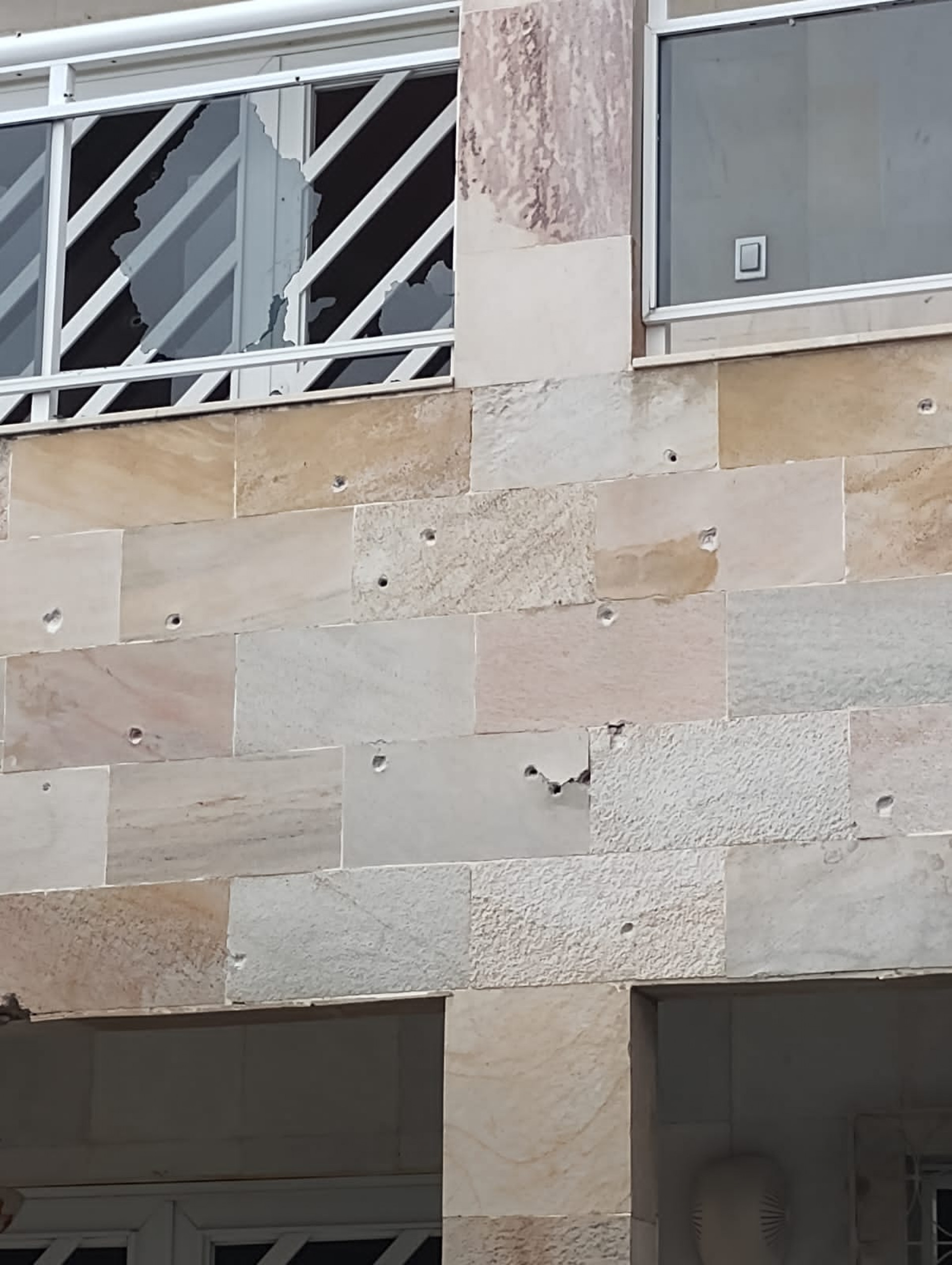 Fachada da residência com marcas dos disparos e os vidros da sacada quebrados