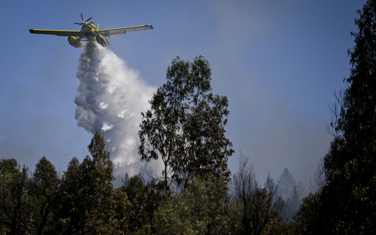 Avião do Corpo de Bombeiras lança água sobre as chamas