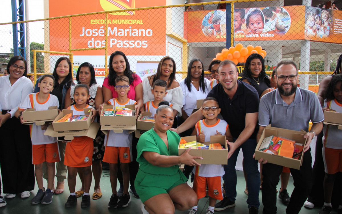 Matheus Carneiro e Denis Macedo com alunos e responsáveis na entrega de kits escolares