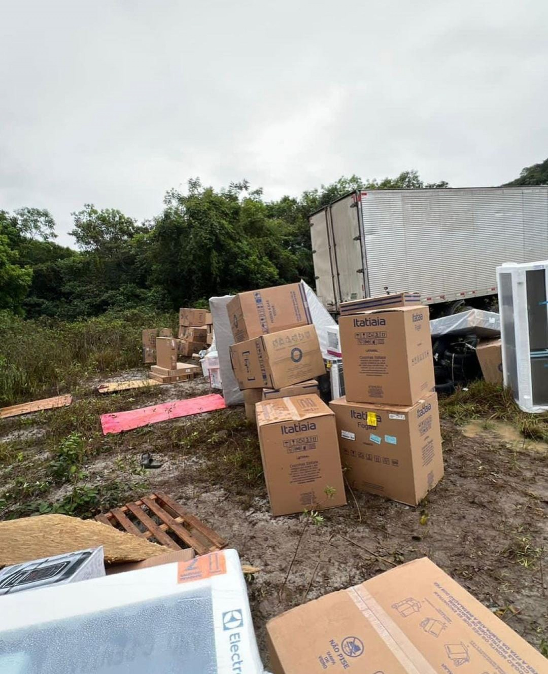 Carga contendo televisores e outros eletrodomésticos é transferida de um caminhão para outro em Guapimirim