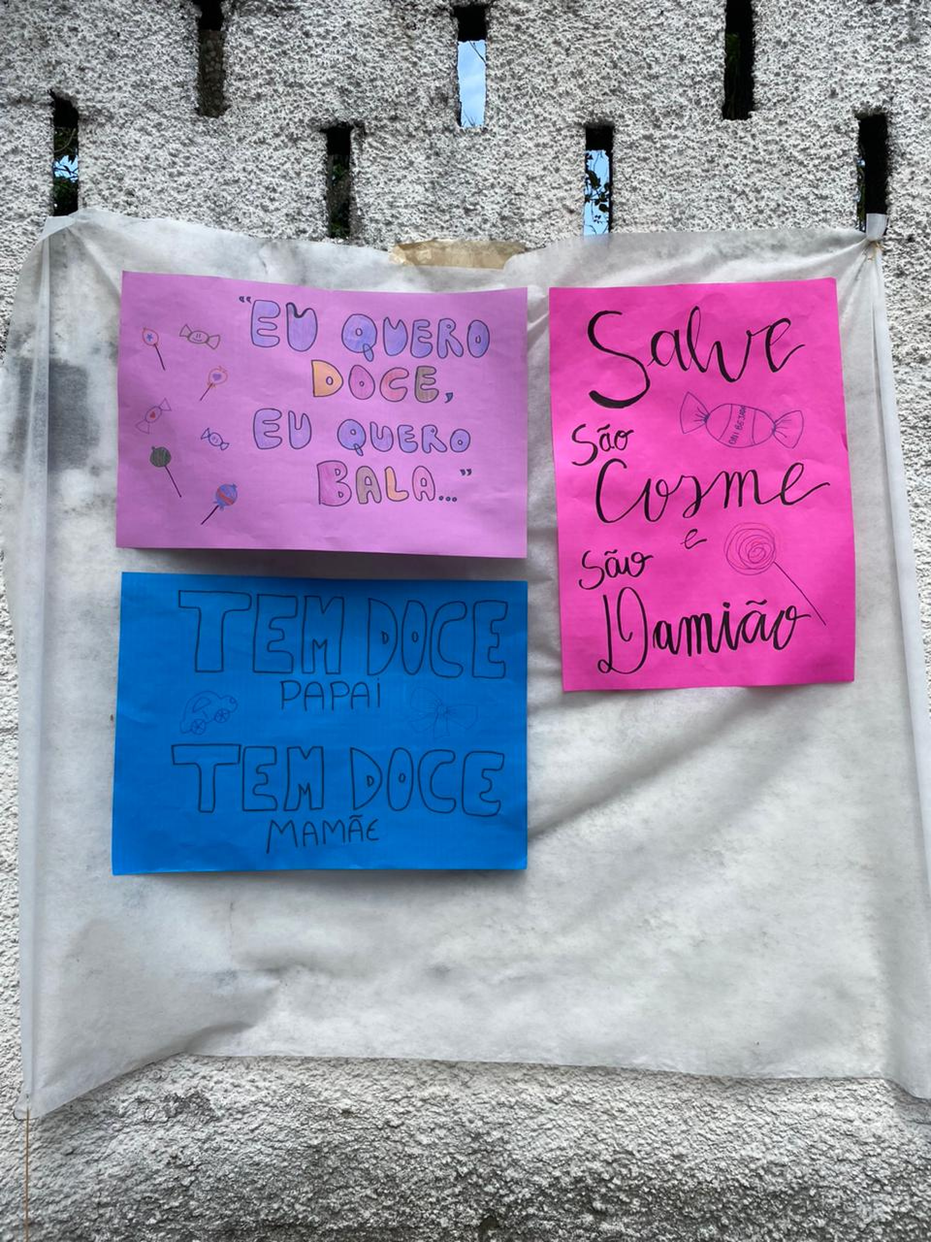 Cartazes no terreiro avisam da distribuição de doces em homenagem a São Cosme e São Damião