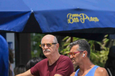 Marcos Caruso caminha ao lado do namorado em Ipanema