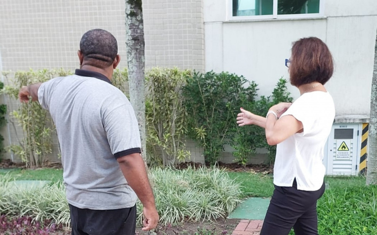 A síndica Maria Esperanza conversa com um funcionário sobre questões da jardinagem do condomínio