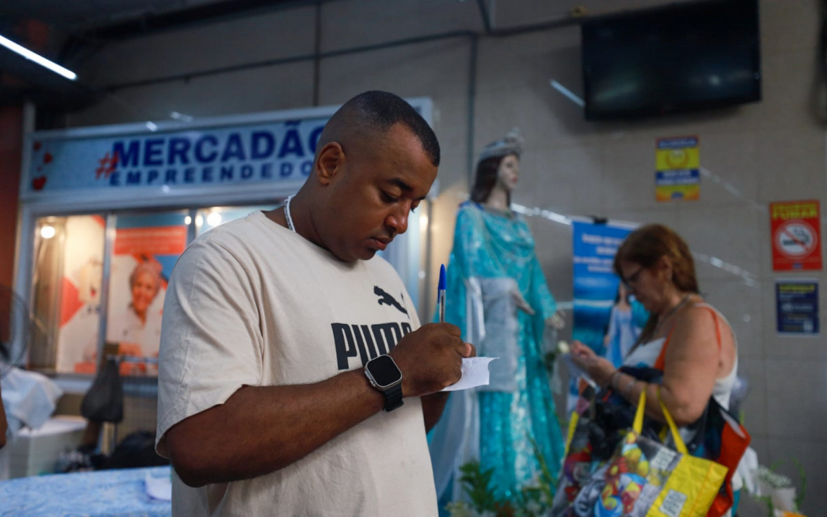 Leandro da Silva Fontes, 40 anos, escreve seus pedidos para Iemanjá no Mercadão de Madureira, na tarde desta sexta-feira (29)   - Renan Areias / Agência O Dia
