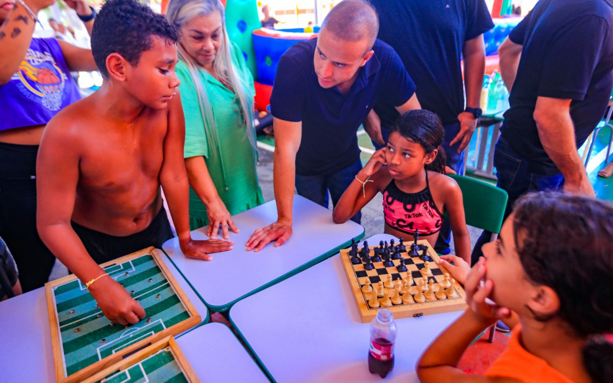 Secretário Matheus Carneiro observa alunos jogando xadrez durante a colônia de férias