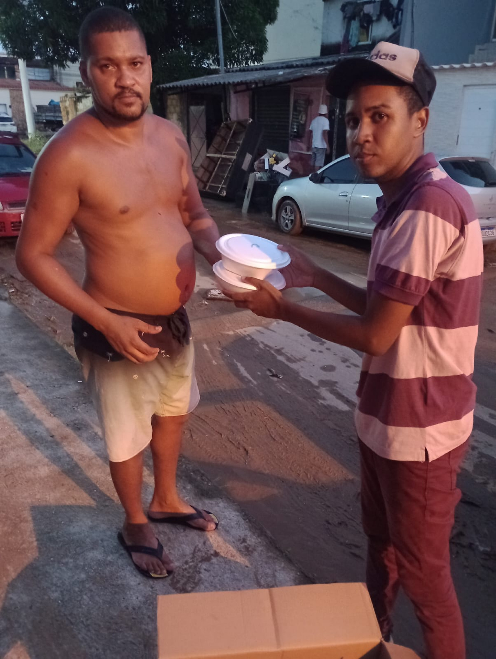 Morador recebendo uma quentinha doada por um componente da escola de samba belforroxense - Divulgação