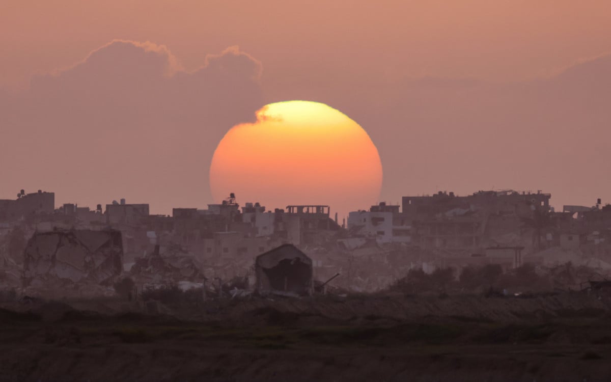 Pôr do sol entre prédios destruídos na Faixa de Gaza - AFP