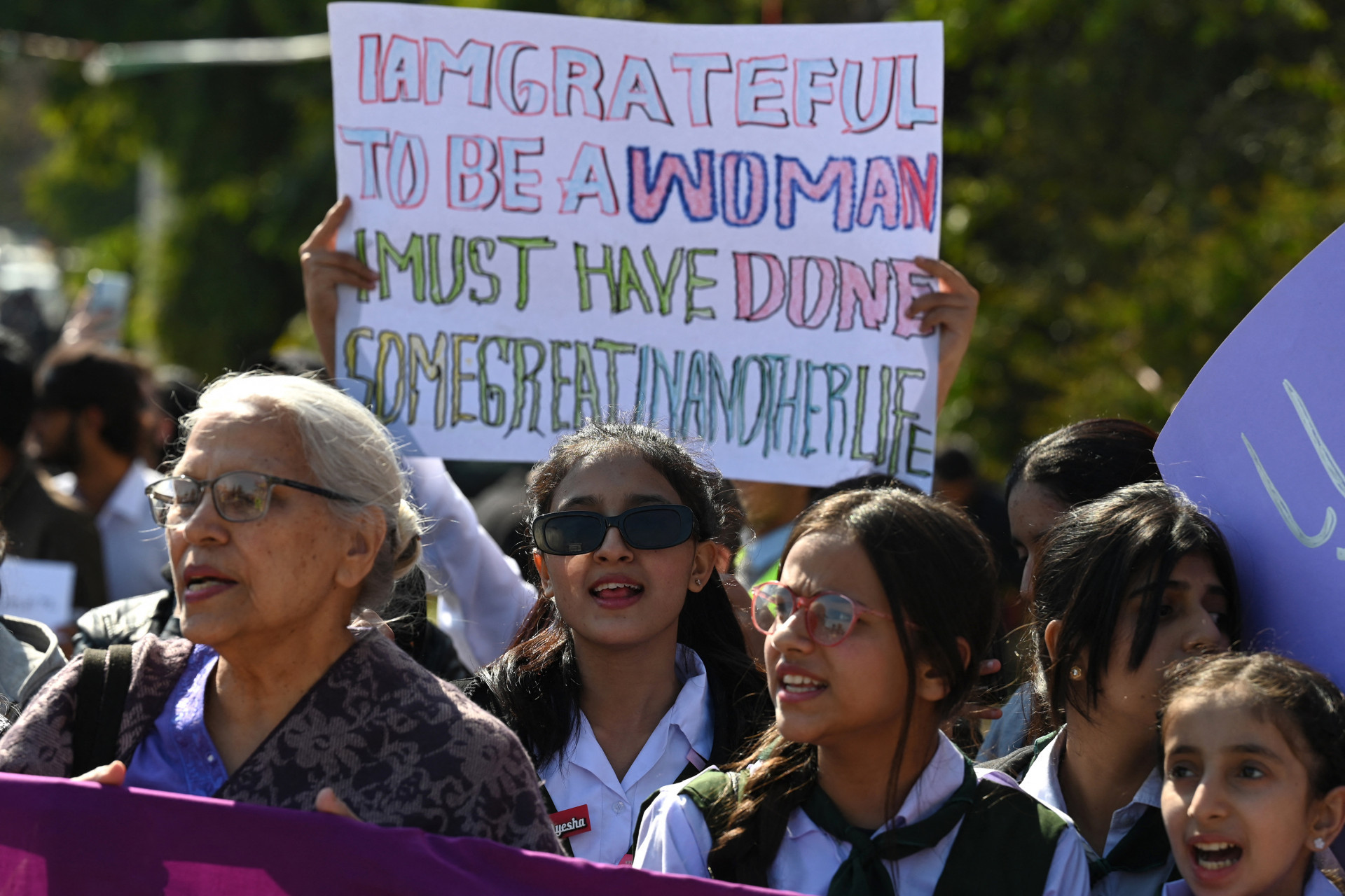 Mulher com cartaz 'Sou grata por ser mulher. Devo ter feito algo bom em outra vida' durante protesto no Paquistão - Aamir Qureshi / AFP